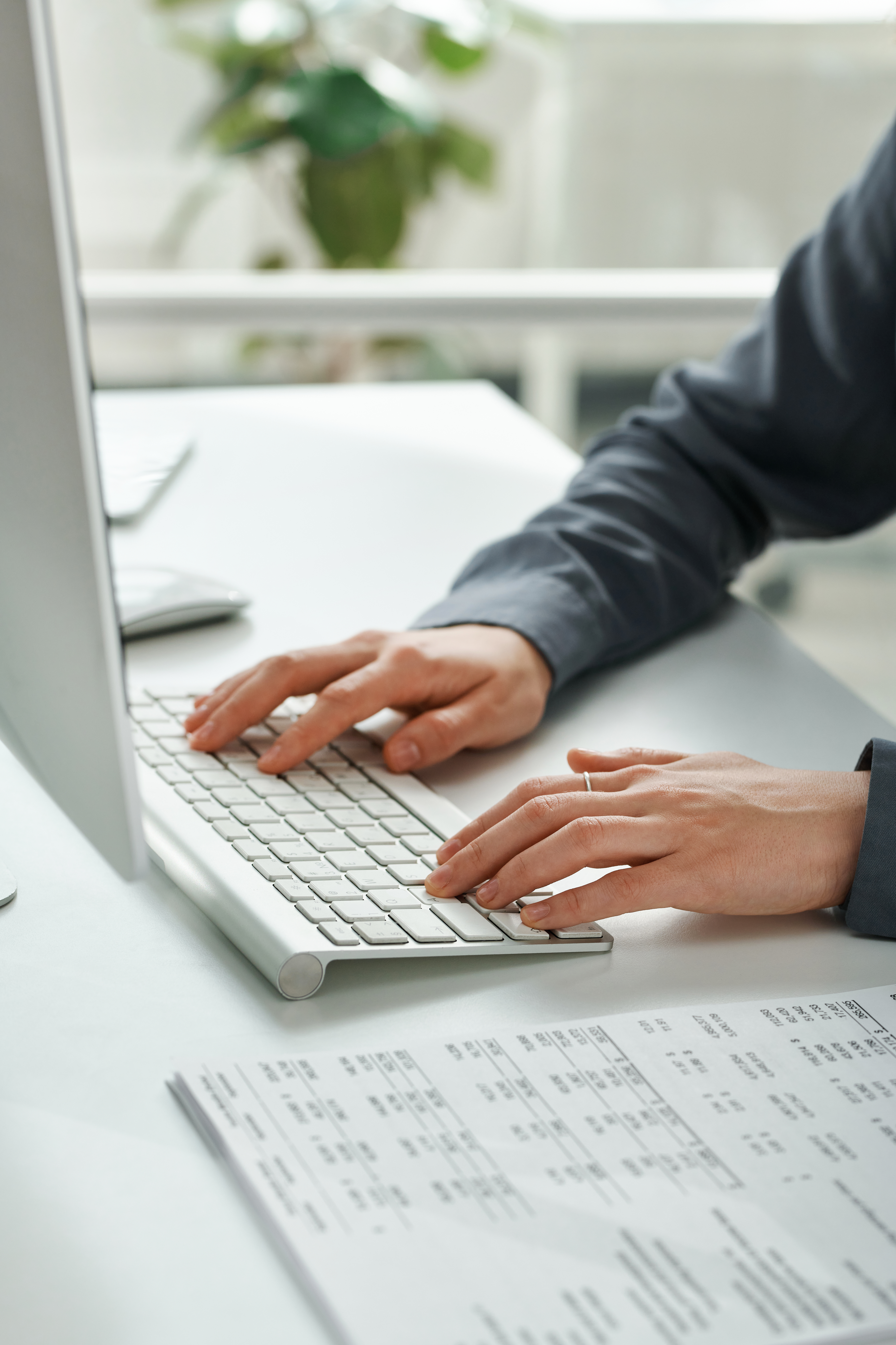 Close-up of female manager typing document on computer keyboard at her table at office